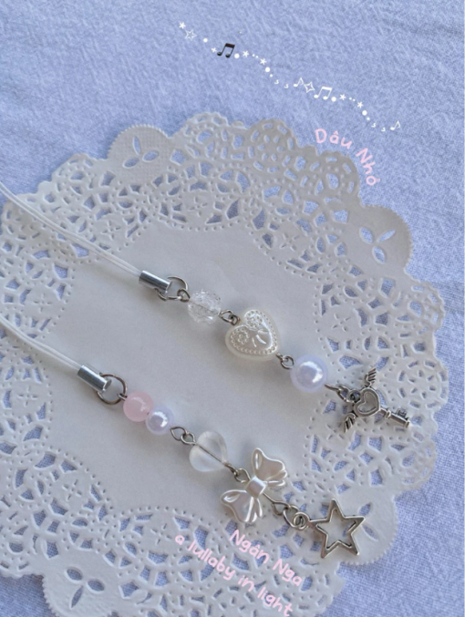 Móc khoá handmade “Thì Thầm Thiên Thần” là bộ sưu tập lấy cảm hứng từ những lời thì thầm dịu dàng của thiên thần gửi đến trái tim người nhận. Sản phẩm kết hợp các chất liệu như hạt pha lê, ngọc trai nhân tạo, charm kim loại hình trái tim, chìa khóa, ngôi sao và nơ. Mang lại vẻ ngoài nhẹ nhàng, trong trẻo nhưng không kém phần mộng mơ. Chất liệu: Dây đeo điện thoại, hạt đá giả thạch anh, hạt pha lê, charm hợp kim không gỉ. Độ dài: ~8–10 cm (tuỳ mẫu)
